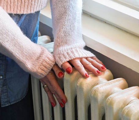 Bild av en kvinna som rör vid en radiator